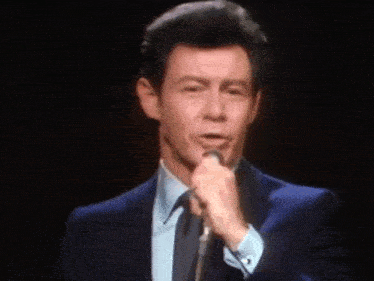 a man in a suit is singing into a microphone .