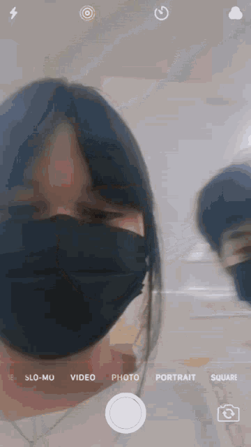 a woman wearing a black face mask is taking a picture