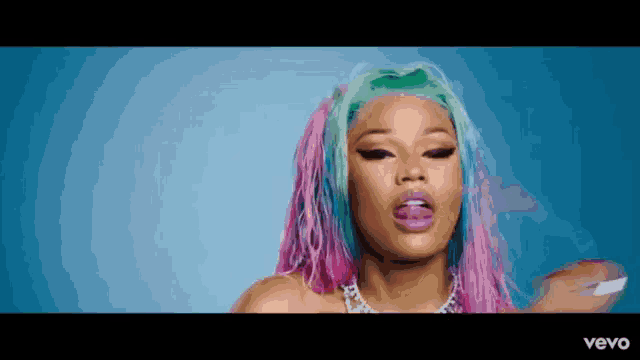a close up of a woman with pink and green hair .