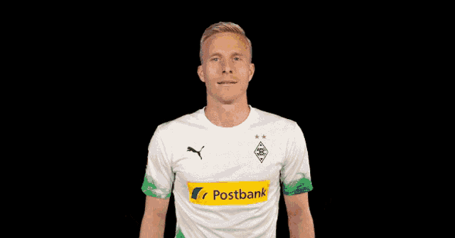 a man wearing a postbank shirt makes a gesture with his hands