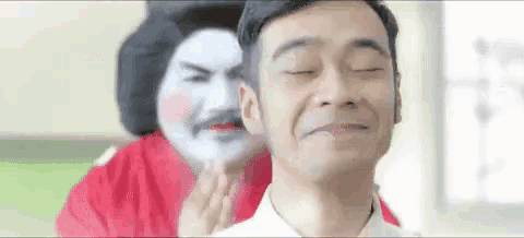 a man is getting a massage from a woman in a geisha costume behind him .