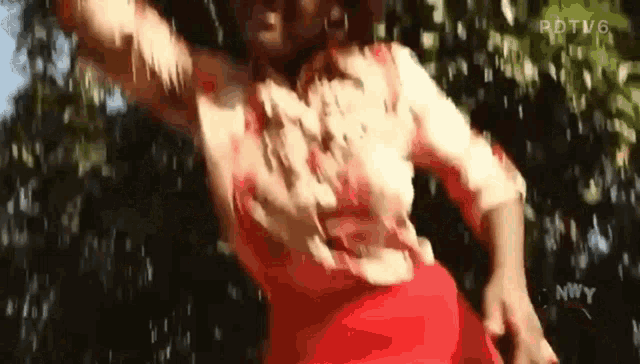 a woman wearing a red skirt and a white shirt is dancing in the rain .