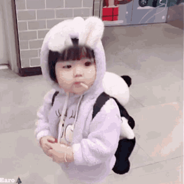 a little girl wearing a bunny costume and a panda backpack smoking a cigarette