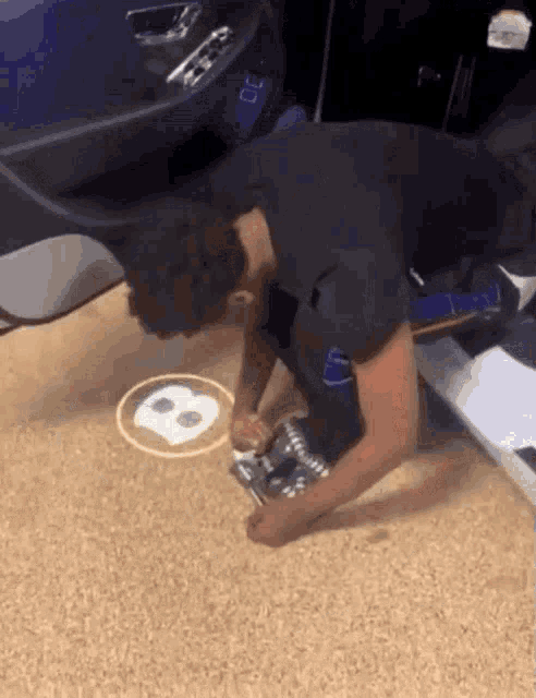 a man is kneeling down in front of a car and drawing a letter b on the floor