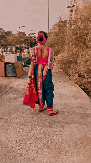 a woman in a pink and blue dress is walking down a street