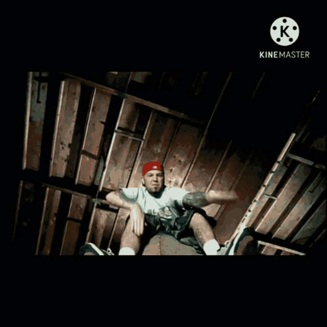 a man in a red hat is sitting on a chair in a dark room with the words kinemaster on the bottom left