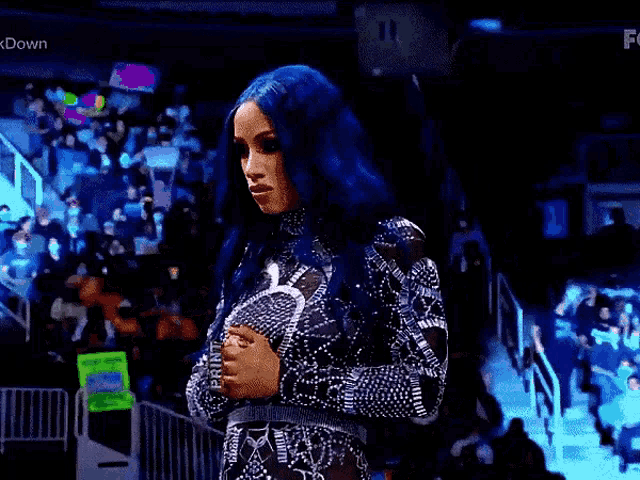 a woman with blue hair is standing in front of a crowd wearing a black and white dress .