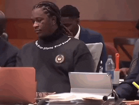 a man in a black sweater is sitting at a table with a laptop .
