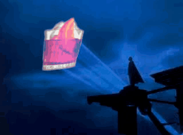 a silhouette of a man standing on top of a building with a sign projected on the wall above him