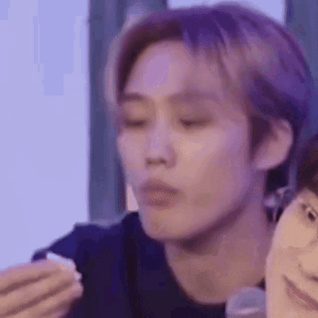 a close up of a person eating a sandwich with a purple background .