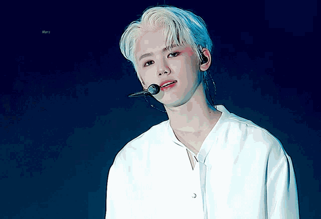 a young man with blonde hair is wearing a white shirt and a microphone
