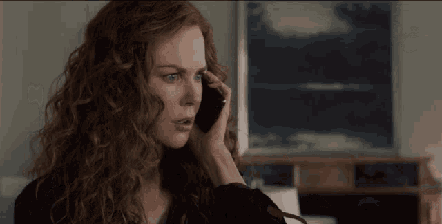 a woman with red hair is talking on her cell phone