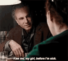 a man and woman are sitting at a table with the man saying kiss me my girl before i 'm sick