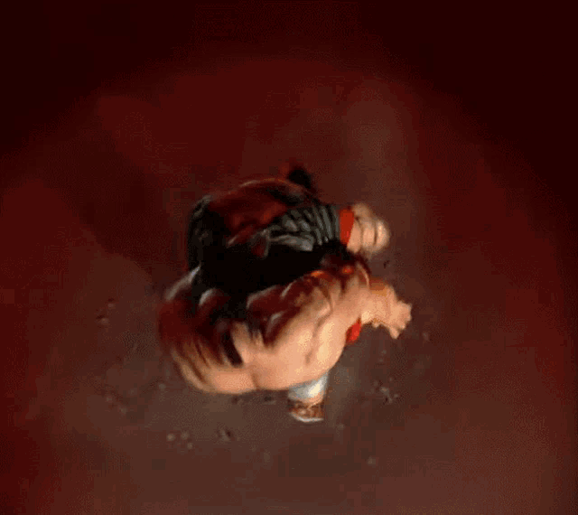 two men are wrestling in a dark room and one of them is wearing a red shirt