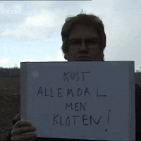 a man holds a sign that says kust allemaal men kloten