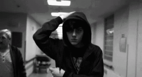 a man in a hooded jacket is standing in a hallway .