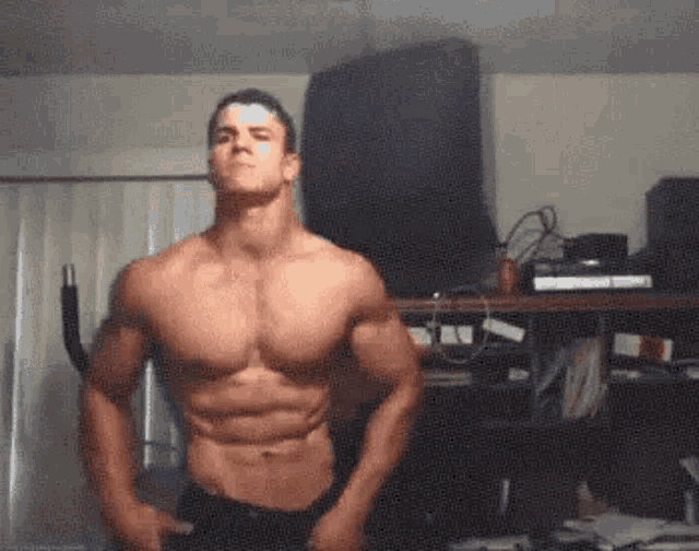 a shirtless man is flexing his muscles in a living room .
