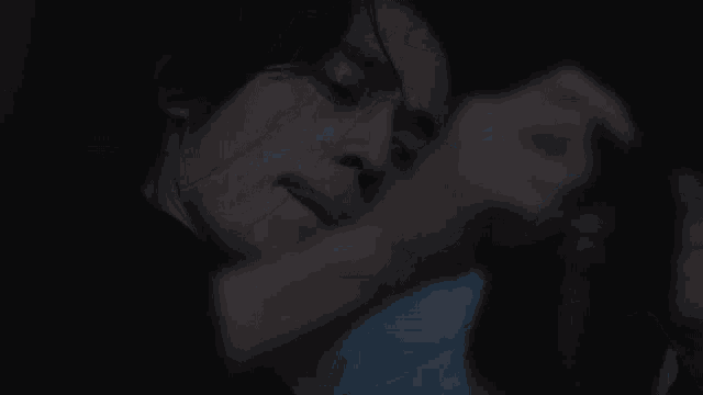 a man and a woman are laying on a bed and kissing in the dark .
