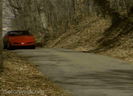 a red pontiac is driving down a road with motorweek.org written on the bottom