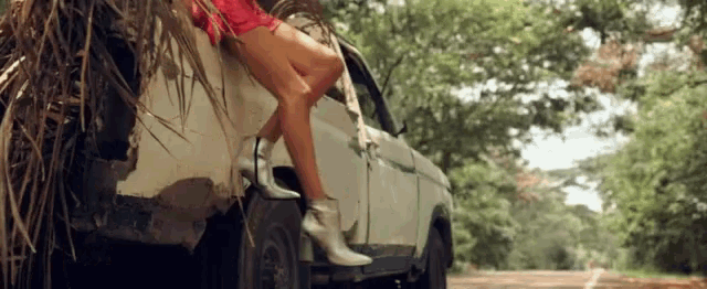 a woman is sitting on the back of a car with her legs crossed .