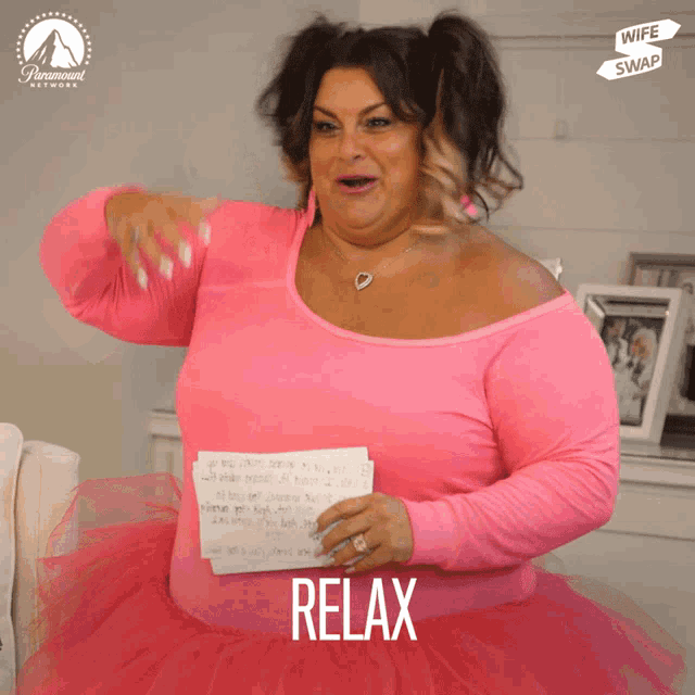 a woman in a pink tutu is holding a piece of paper with the word relax on it