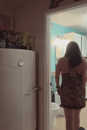 a woman in a leopard print dress is standing in a hallway