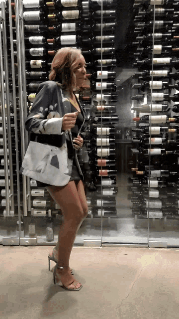 a woman is standing in front of a wall of wine