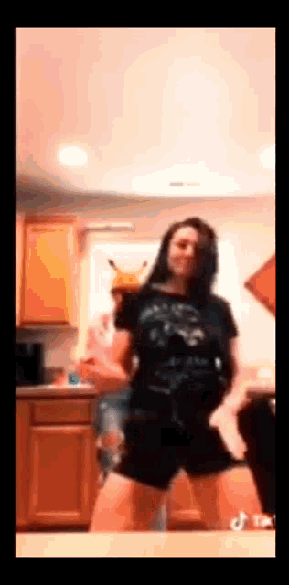 a woman in a black shirt is dancing in a kitchen .