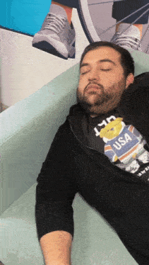 a man is sleeping on a couch wearing a usa polo bear shirt