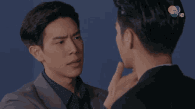 two men are looking at each other and one has a hand on his chin