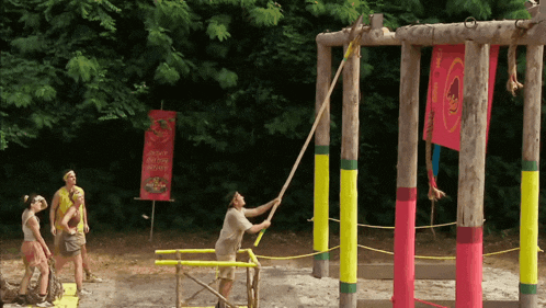 a group of people are playing a game with a banner that says ' survivor ' on it in the background