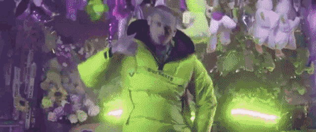 a man in a neon yellow jacket is standing in front of a bunch of balloons .