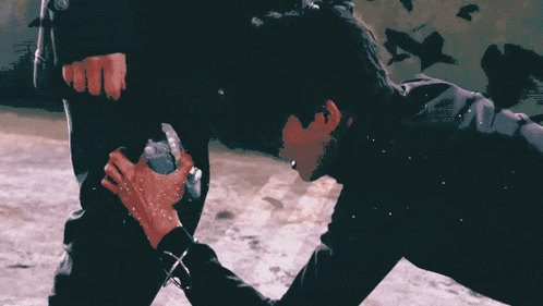 a man in a black jacket is kneeling down and holding something