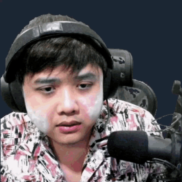 a man with a bandage on his face is wearing headphones and a microphone .