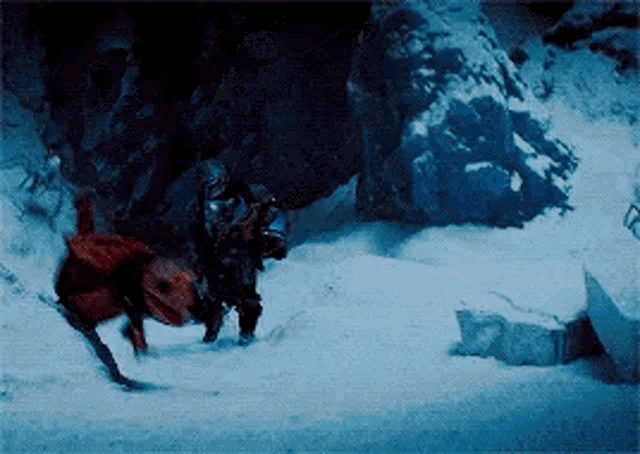 a man is riding a horse in the snow while another man looks on .