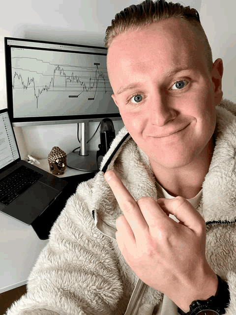 a man is giving the middle finger in front of a computer screen