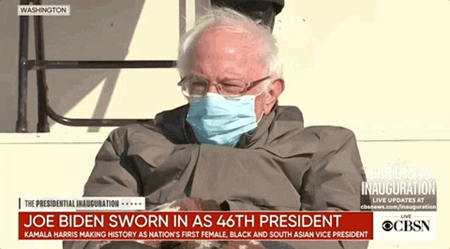 a man wearing a face mask is sitting in front of a cbs news broadcast