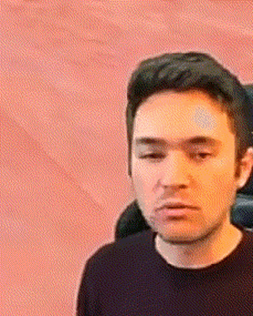 a man in a black shirt is sitting in a chair with his eyes closed .