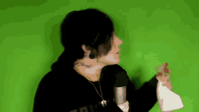 a man with a tattoo on his neck is holding a spray bottle and a microphone .
