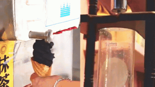 a person is holding an ice cream cone in front of a machine that says ' ice cream ' on it