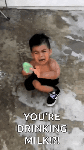 a little boy is sitting on the ground holding a soap bar and crying .