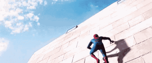 a man in a spiderman suit is climbing a brick wall .