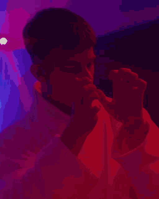 a man in a white robe is standing in a dark room with blue lights behind him