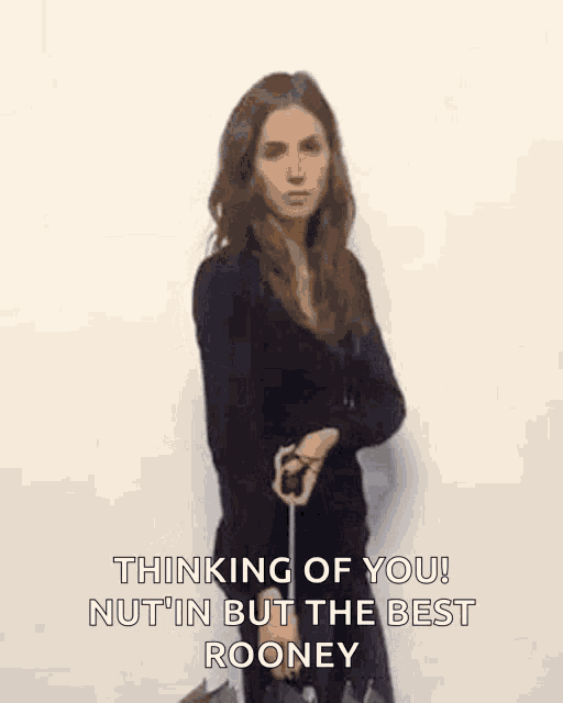 a woman is standing in front of a white wall holding an umbrella and a cane .