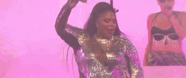 a woman in a sequined dress is dancing on a stage with a microphone .