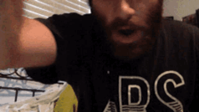 a man with a beard is wearing a black shirt that says dc