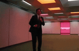 a man in a suit and tie is dancing in a room with red lights