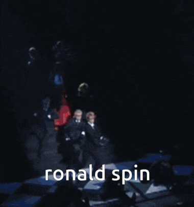 a man in a suit and tie is dancing on a stage with the words ronald spin above him .