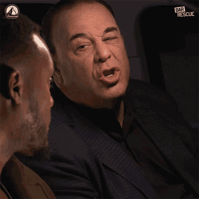 a man in a suit is talking to another man in a bar rescue poster