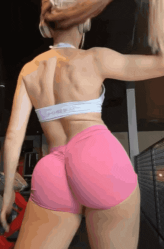 a woman wearing pink shorts and a sports bra that says poke butt